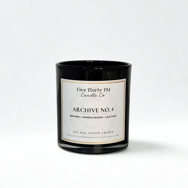 Archive No. 4 Presence candle by Five Thirty PM Candle Co® in a black glass jar with brandy, sandalwood, and leather fragrance notes.
