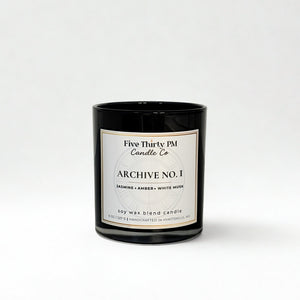 Archive No. 1 First Light candle by Five Thirty PM Candle Co® in a black glass jar with jasmine, amber, and white musk fragrance notes.