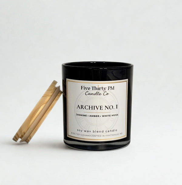 Archive No. 1 First Light candle by Five Thirty PM Candle Co® in a black glass jar with a wooden lid and notes of jasmine, amber, and white musk.