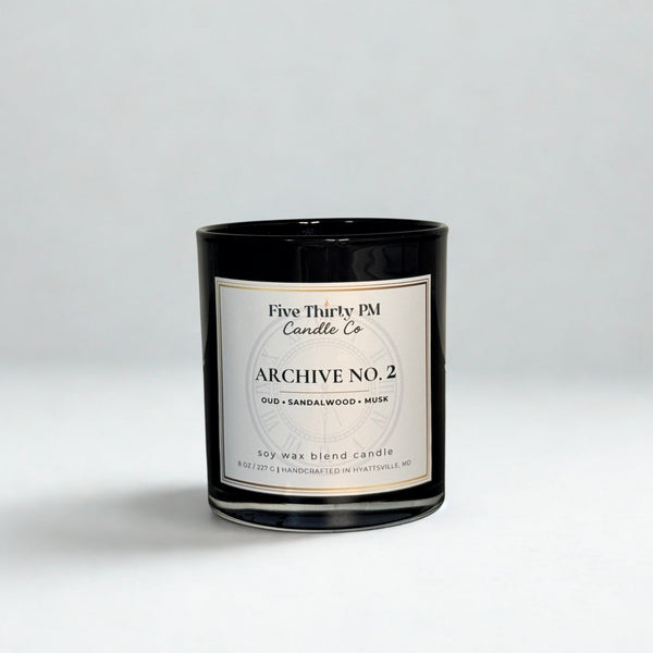 Archive No. 2 Becoming candle by Five Thirty PM Candle Co® in a black glass jar with oud, sandalwood, and musk fragrance notes.