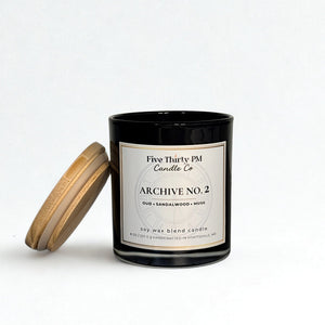 Archive No. 2 Becoming candle by Five Thirty PM Candle Co® in a black glass jar with a wooden lid and oud, sandalwood, and musk fragrance notes.