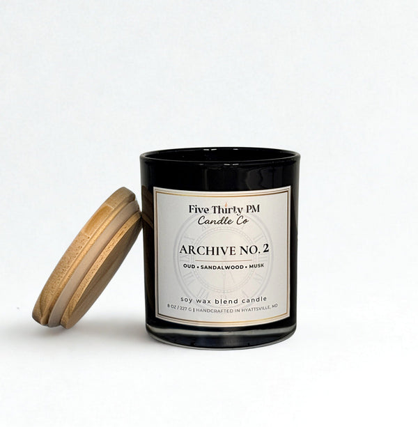 Archive No. 2 Becoming candle by Five Thirty PM Candle Co® in a black glass jar with a wooden lid and oud, sandalwood, and musk fragrance notes.