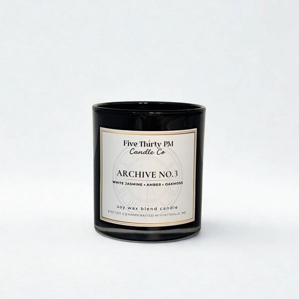 Archive No. 3 Becoming Still candle by Five Thirty PM Candle Co® in a black glass jar with white jasmine, amber, and oakmoss fragrance notes.