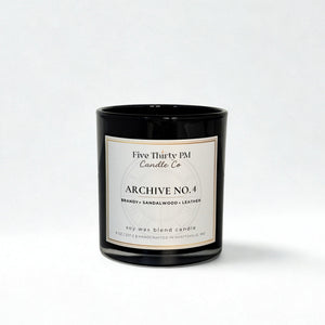 Archive No. 4 Presence candle by Five Thirty PM Candle Co® in a black glass jar with brandy, sandalwood, and leather fragrance notes.