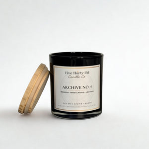 Archive No. 4 Presence candle by Five Thirty PM Candle Co® in a black glass jar with a wooden lid and brandy, sandalwood, and leather fragrance notes.