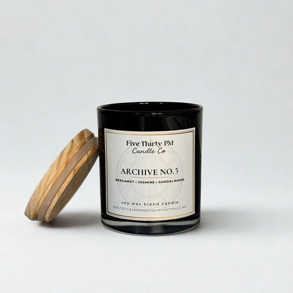 Archive No. 5 Devotion candle by Five Thirty PM Candle Co® in a black glass jar with a wooden lid and bergamot, jasmine, and sandalwood fragrance notes.
