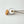 Gold-finish stainless steel wick trimmer with engraved Five Thirty PM Candle Co® logo being used to trim a candle wick for a cleaner burn.