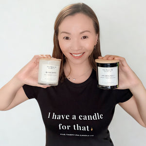 Ivy, founder and candle maker of Five Thirty PM Candle Co®, holding Blush Hour and Archive No. 5 candles while wearing an “I have a candle for that” T-shirt.