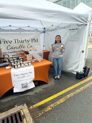 Ivy, founder and candle maker of Five Thirty PM Candle Co®, standing inside her outdoor market booth with displays of handcrafted candles, wax melts, and candle accessories at Fall Festival Mosaic District hosted by URBN market.
