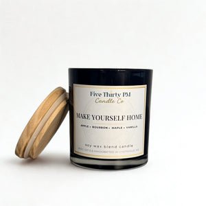 Make Yourself Home candle by Five Thirty PM Candle Co® in a black glass jar with a wooden lid and apple, bourbon, maple, and vanilla fragrance notes.