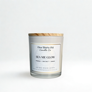 Sea Me Glow candle by Five Thirty PM Candle Co® in a white glass jar with wooden lid, featuring freesia, sea salt, and amber fragrance notes.