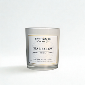 Open Sea Me Glow candle by Five Thirty PM Candle Co® in a white glass jar, featuring freesia, sea salt, and amber fragrance notes.